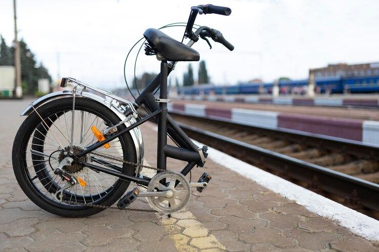 Un vélo électrique plié au bord d'une ligne de chemin de fer