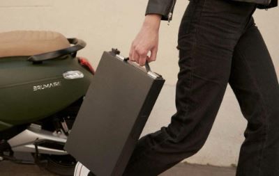 Personne transportant une batterie d’un scooter électrique Brumaire près d’un modèle 4700W vert