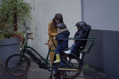 Une femme installant deux enfants à l’arrière d’un Brumaire Nébula vert anglais