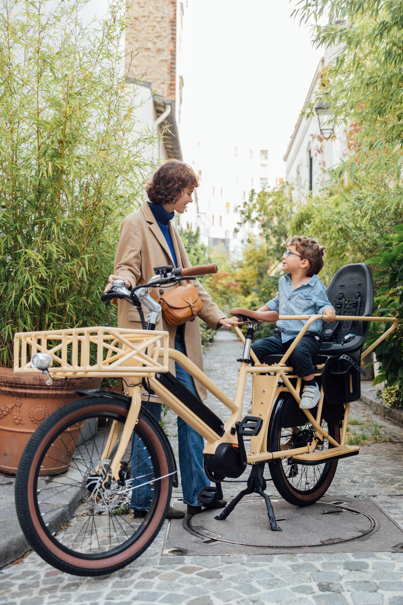 Une femme et son enfant sur un vélo cargo beige