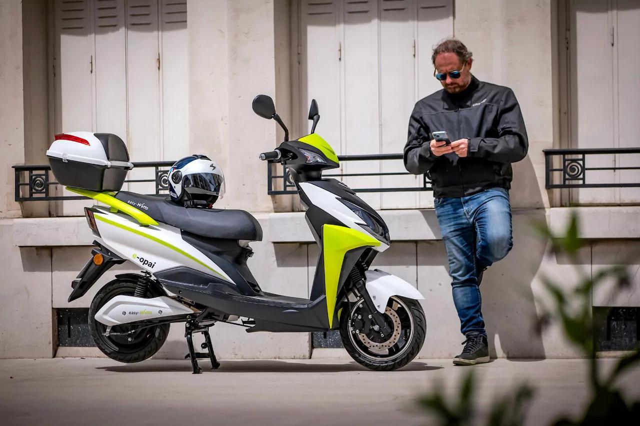 Un homme sur son téléphone à côté d"un scooter électrique