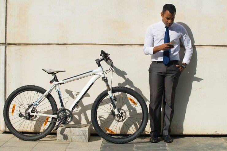 Un homme qui regarde son téléphone contre un mur à côté de son vélo