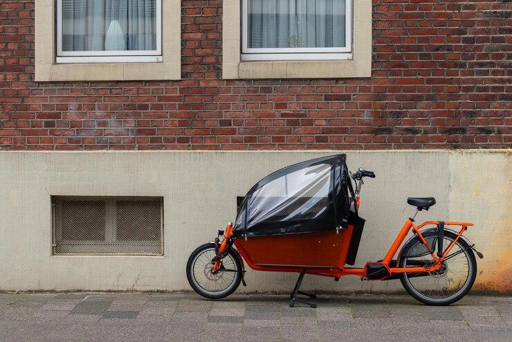 Un vélo cargo rouge et noir dans une ruelle