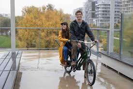 Deux adultes sur un vélo électrique cargo vert